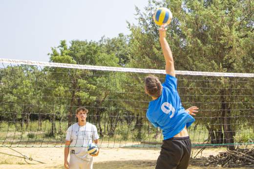 2 joueurs de volley, chacun dun côté du filet et un qui va taper dans le ballon