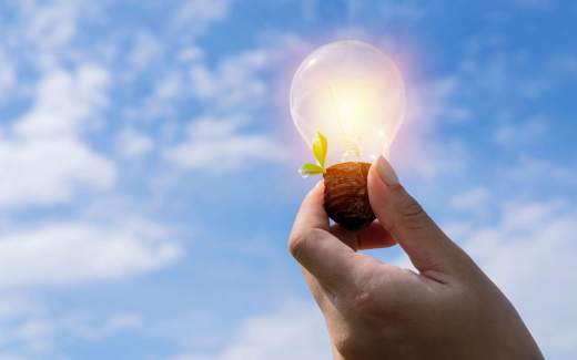 Activité scolaire science : la transformation des énergies Photo de lactivité scolaire science : transformation des énergies, montrant une main en gros plan qui tient une ampoule vers le ciel bleu